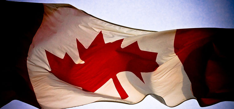 Canadian flag flying against the sun.