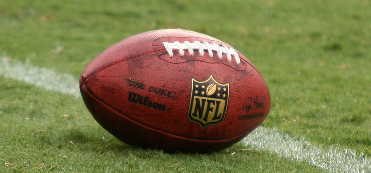 NFL football displayed on turf.