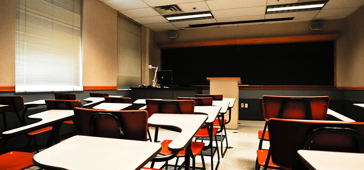 An empty university classroom, red desks.