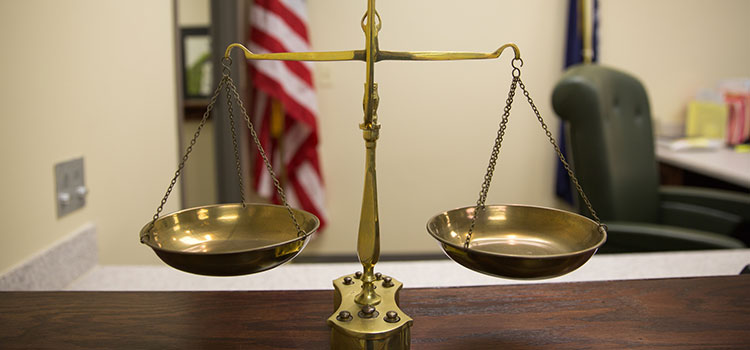 The scales of justice sitting on a courtroom table.