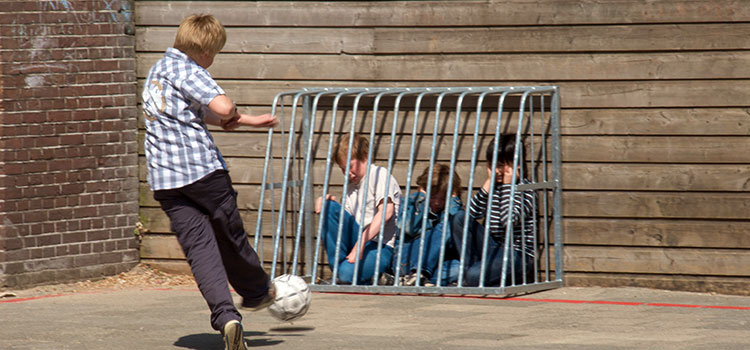 School-yard bully kicking a soccer ball at unhappy students.