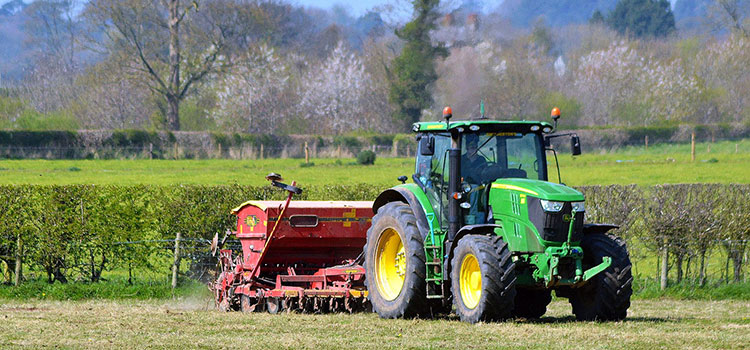 Green tractor doing field work in California.