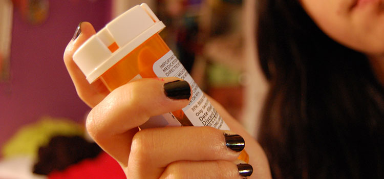 A woman holds a bottle of prescription painkillers. Opiate addiction is a serious issue and has become a leading cause of death among addicts.