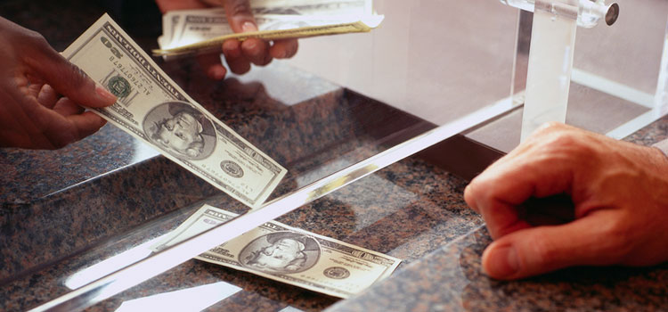 Cash changing hands during an exchange with a bank teller.