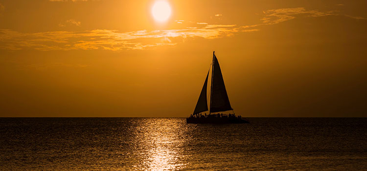 A sailboat silhouetted by the setting sun somewhere in the Cayman Islands.