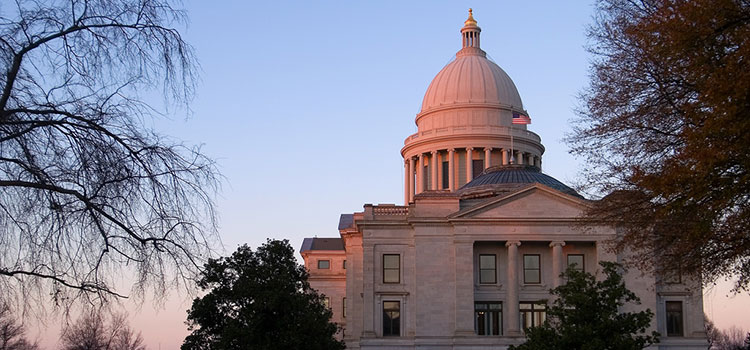 The capitol building of Arkansas bathed in a sunset's light.