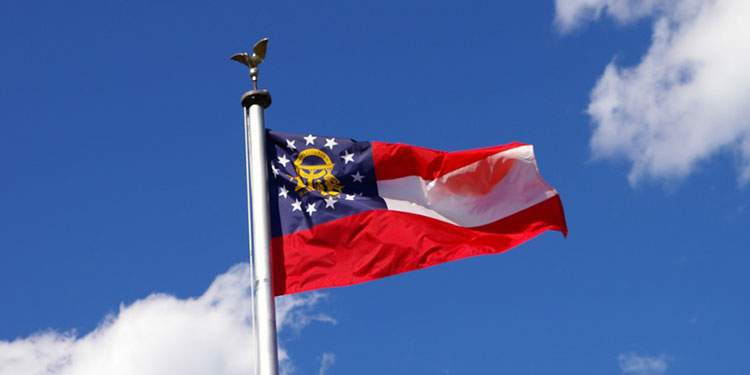 The state flag of Georgia flying on a sunny, blue-skied day.