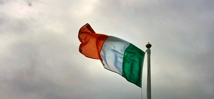 The flag of Ireland flying on a cloudy day.