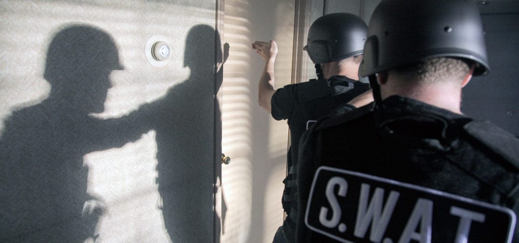 Two SWAT team members preparing to breach a door during a training exercise.