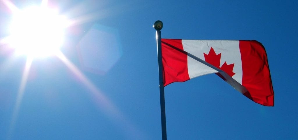 The Canadian flag on a sunny, blue-skied day.