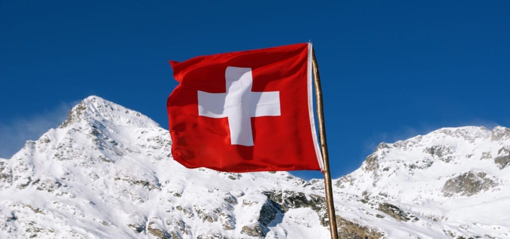 The Swiss flag flies somewhere in the mountains of Switzerland.