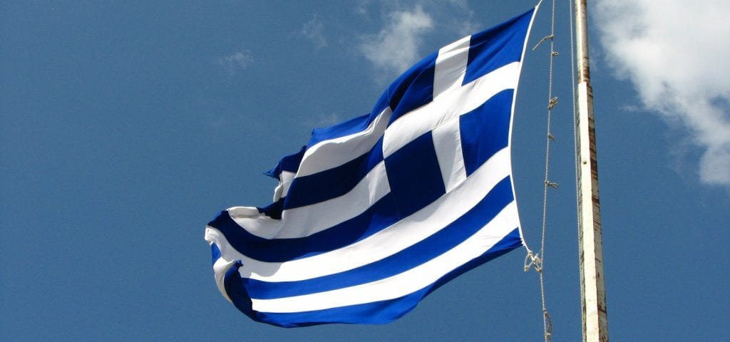 The flag of Greece flying in the sky.