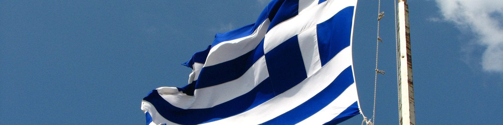 The flag of Greece flying in the sky.