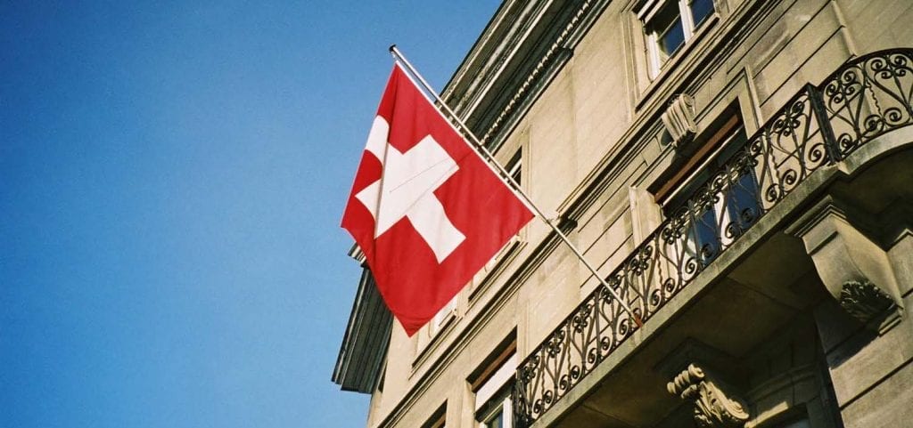 The flag of Switzerland hanging from the exterior of a hotel.