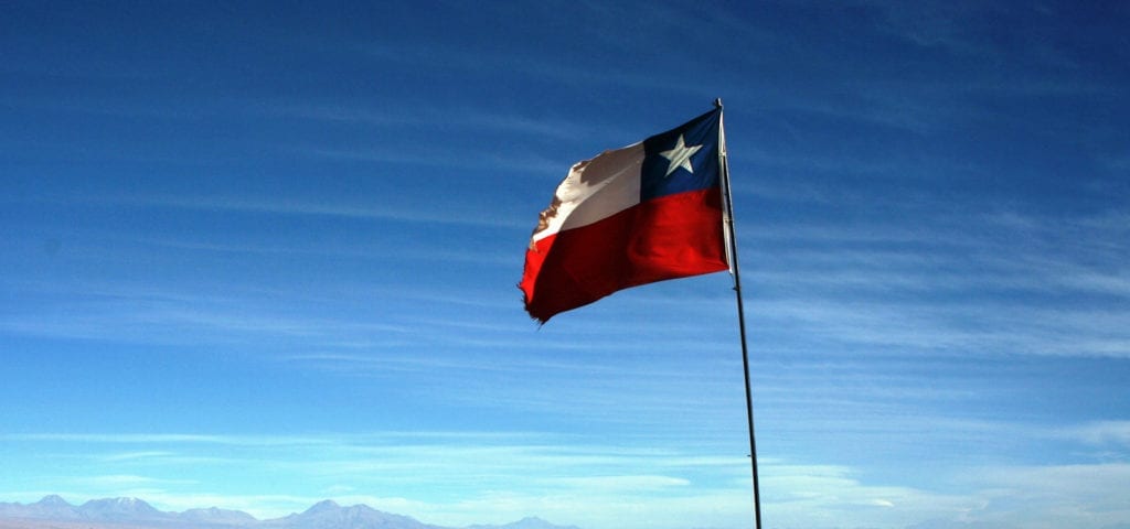 The national flag of Chile flying in the Andes Mountains.