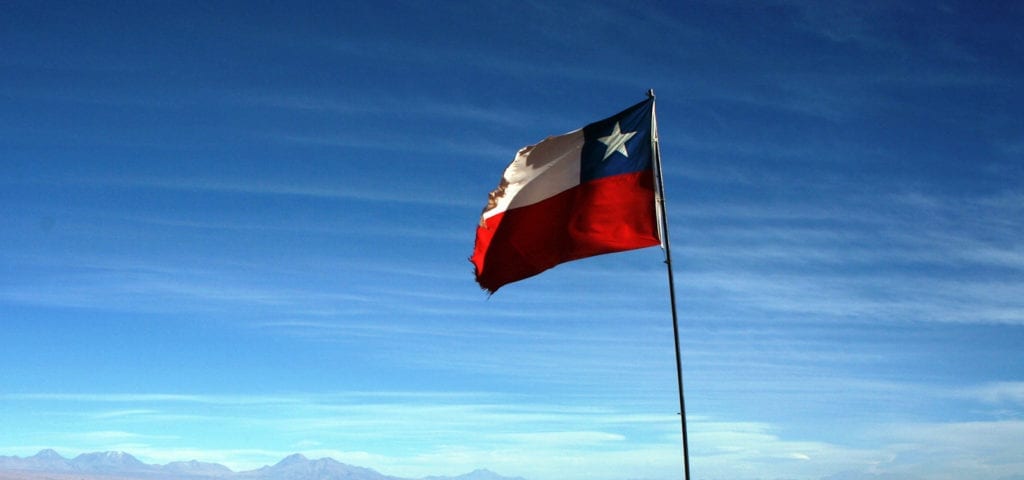 The national flag of Chile flying in the Andes Mountains.