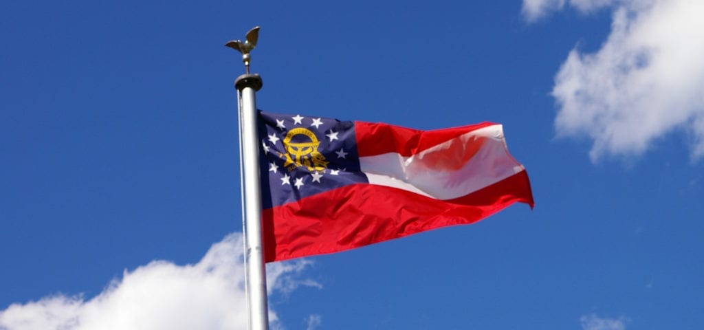 Georgia's state flag flying on a blue-skied, sunny day.