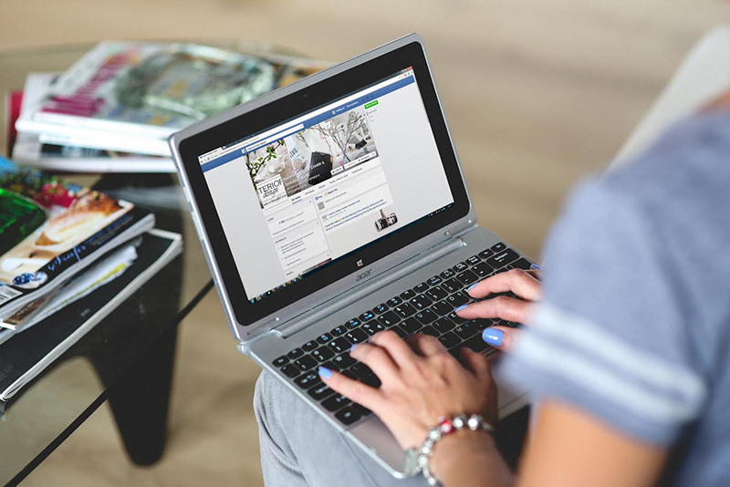 A woman typing information into a Facebook page.