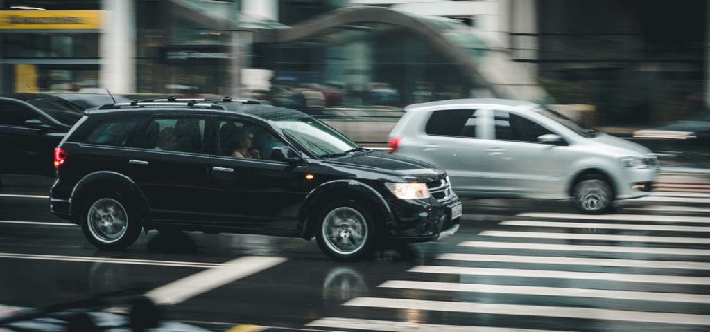 Two cars driving alongside each other among other traffic.