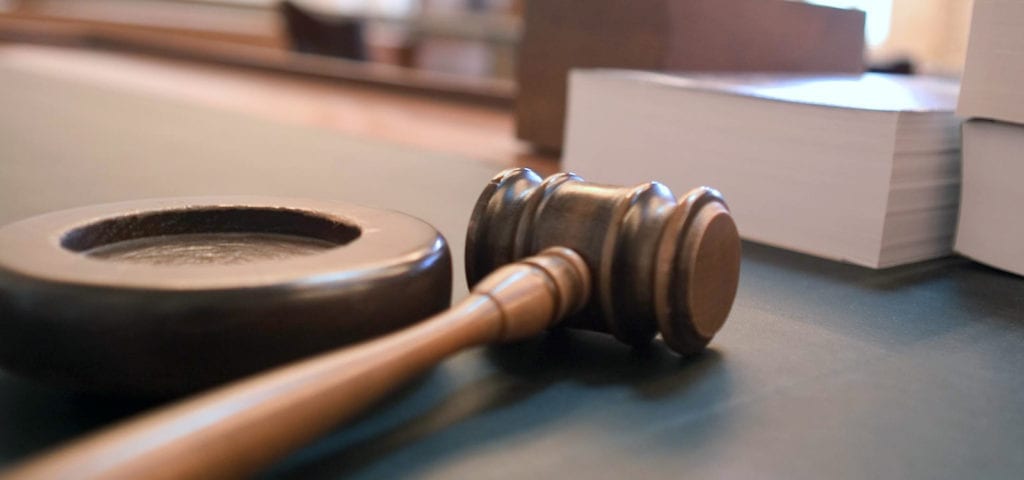 A judge's gavel rests on a desk inside of a U.S. court room.