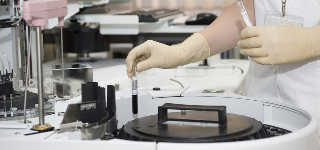 A medical researcher handles medical equipment inside of a sterile work zone.