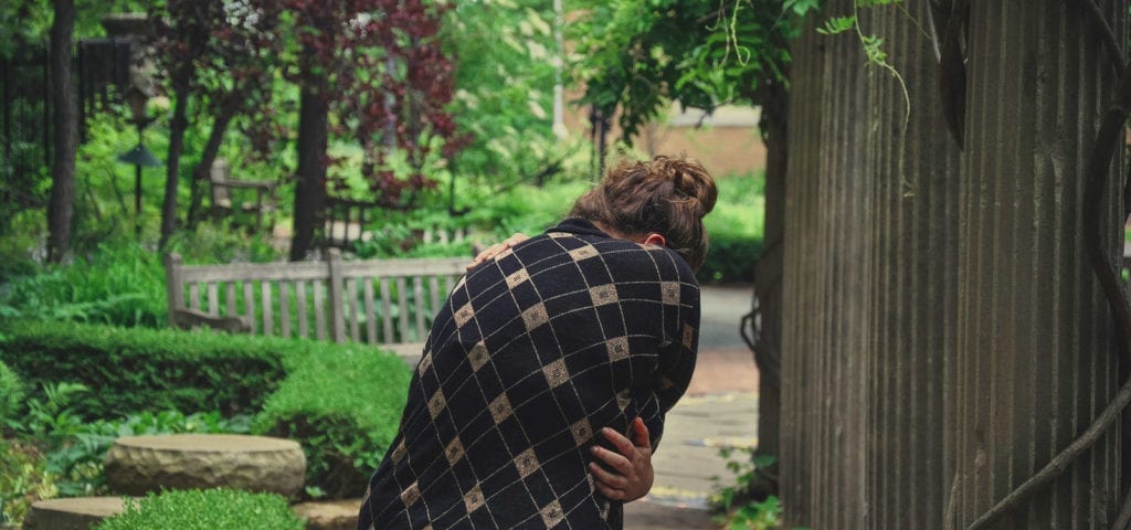 A woman doubled over in pain her backyard.