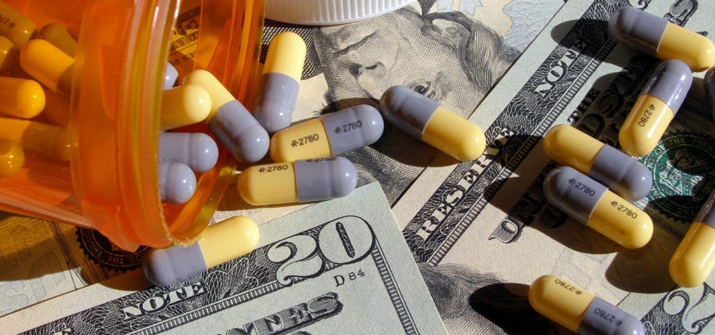 A pile of pharmaceutical pills spilled onto several $20 bills.