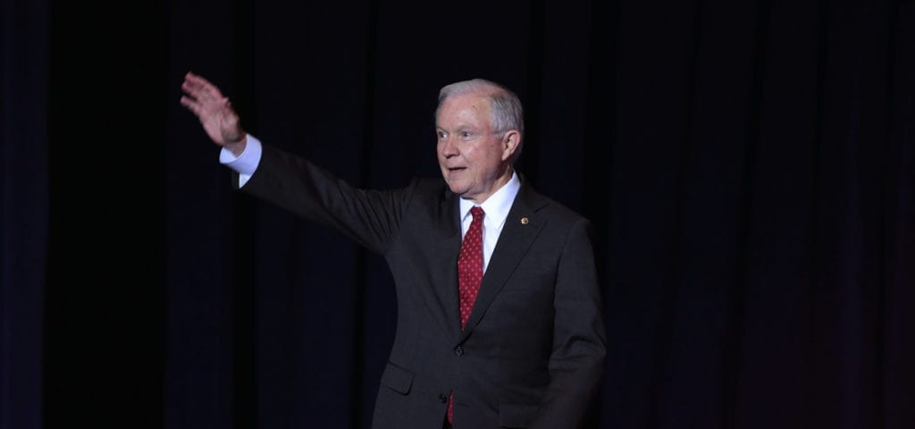 Attorney General Jeff Sessions waving his right hand to a crowd of people.