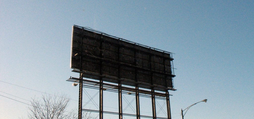 The back of a billboard found on the side of a road.