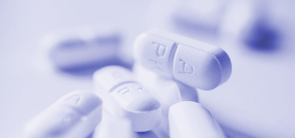 A pile of painkiller medication sitting on a clean, white surface.