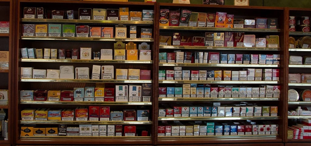 A wall of tobacco products inside of a smoke shop selling cigarettes, cigars, and rolling tobacco.