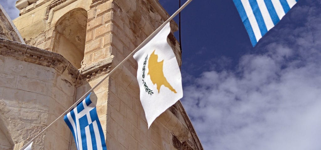The flag of Cyprus hangs on a line next to the flag of Greece during a day of celebration.