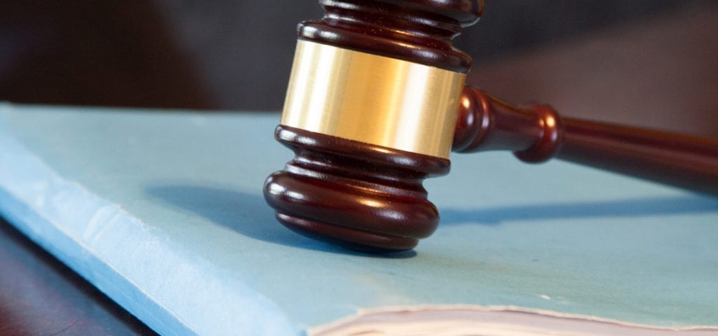 A judge's gavel rests on top of a blue legal notebook.