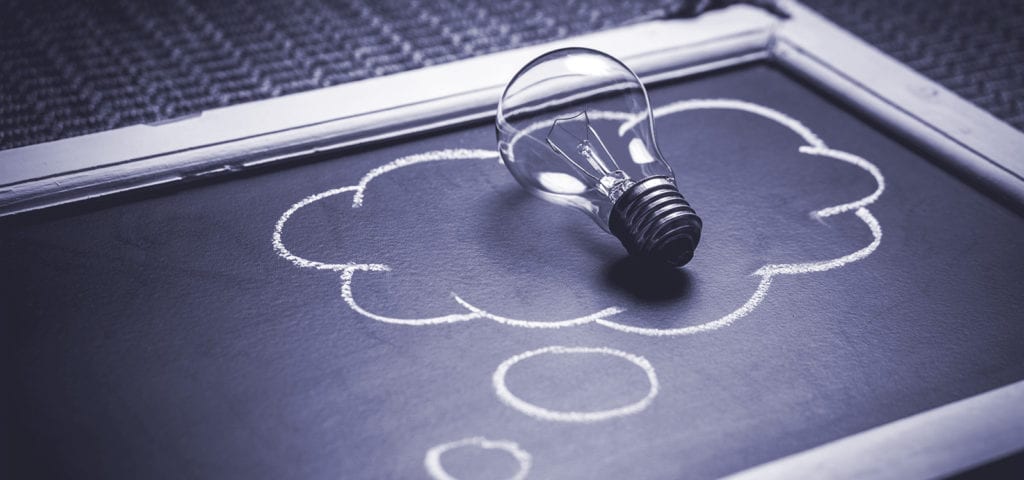A symbolic light bulb sits in the middle of a "thought cloud" drawn on a chalkboard.
