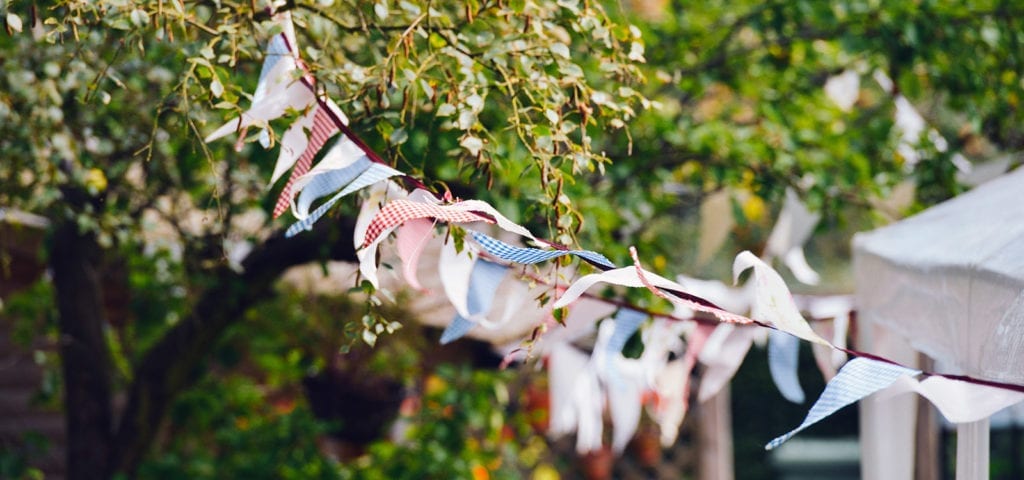 Party flags on a string hang outside in sunny, summer weather.