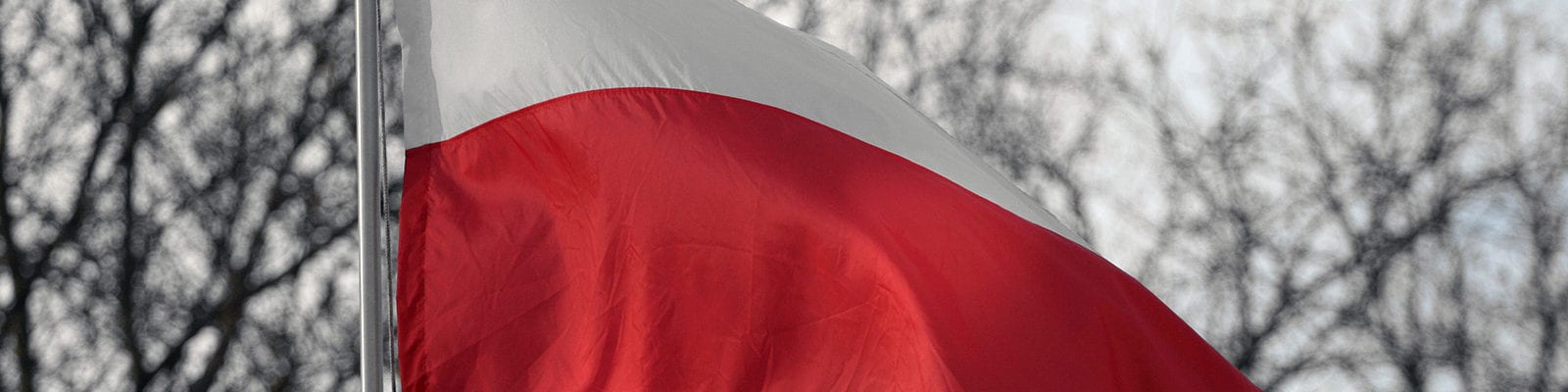 The flag of Poland flying on a windy, cloudy day.