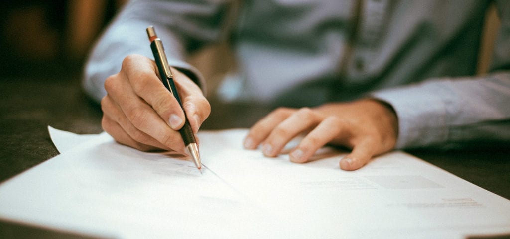 A businessperson signs their signature onto a contractual agreement,