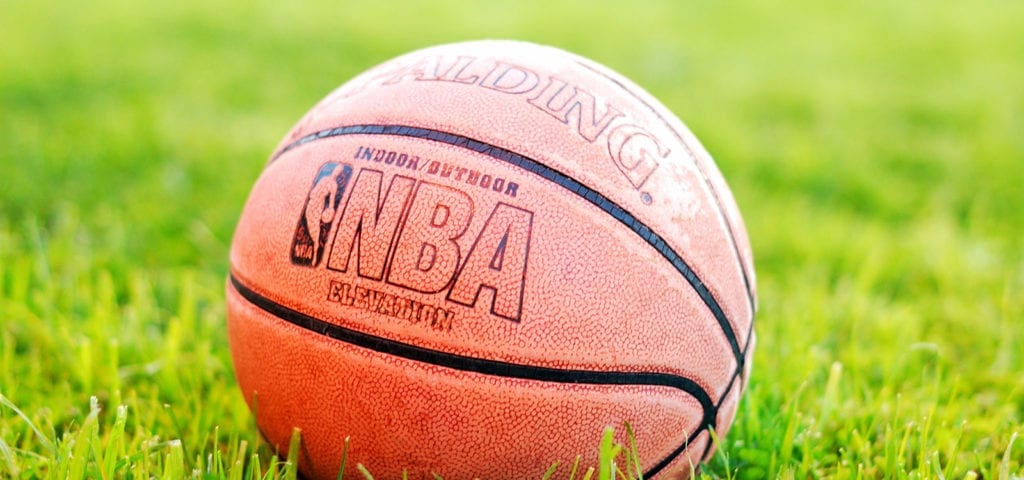 An official NBA Spalding basketball sitting on some grass on a sunny day.