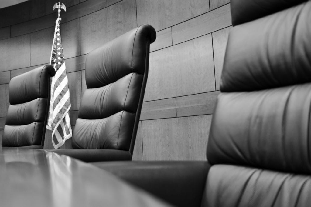 Tall-backed leather chairs sitting at a conference room table.