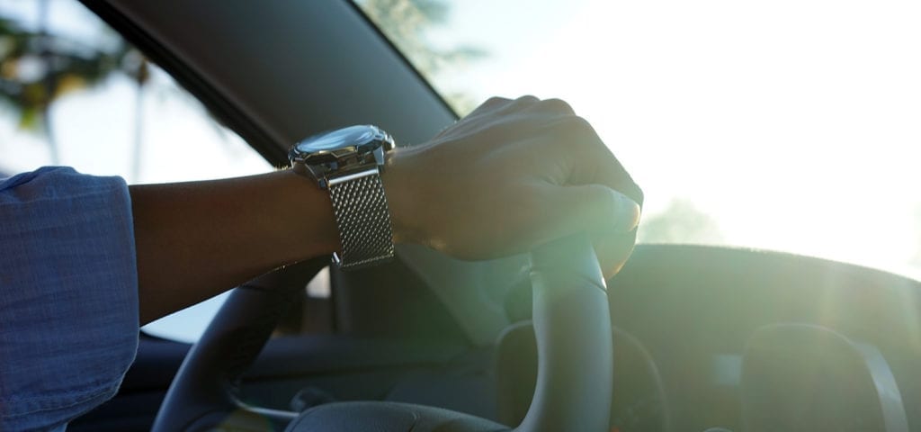 A driver's hand on the steering wheel as they maneuver through traffic.