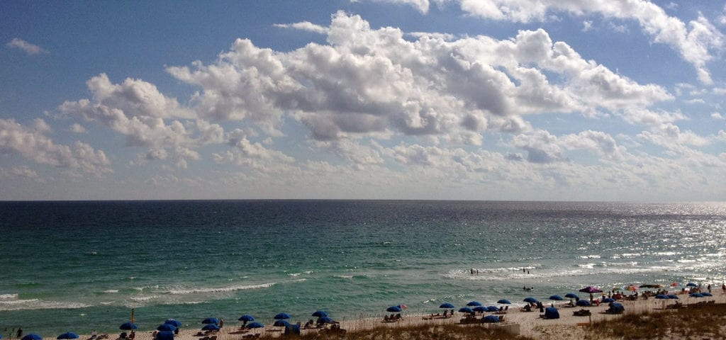 Beach goers hanging out under sun umbrellas on the beach in Florida.