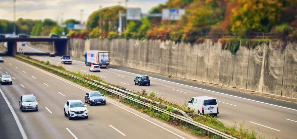 Cars driving down the freeway/highway on a sunny day.