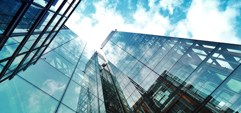 Looking up the walls of a glass office building.
