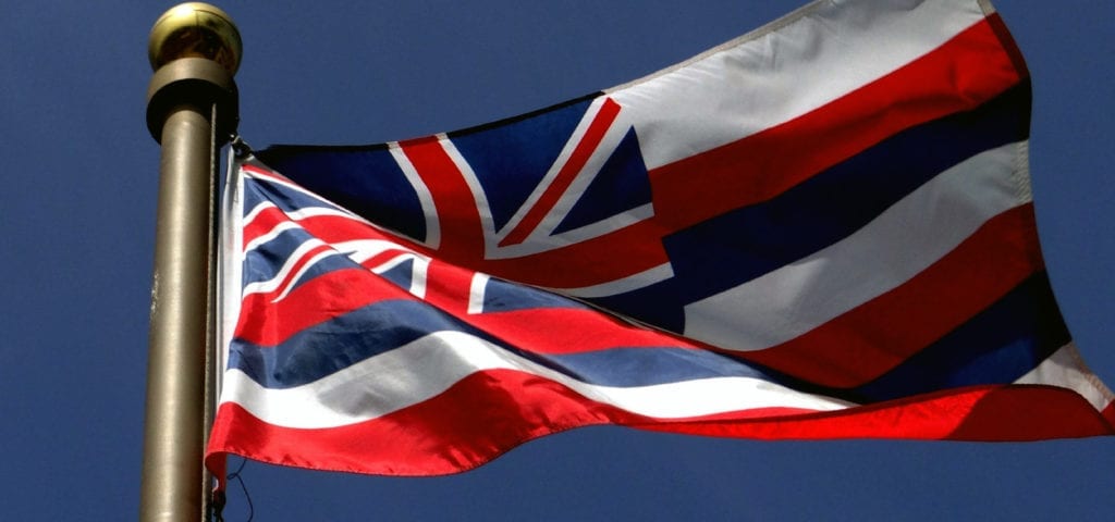 Hawaii's official state flag flying off the back end of a sailboat.