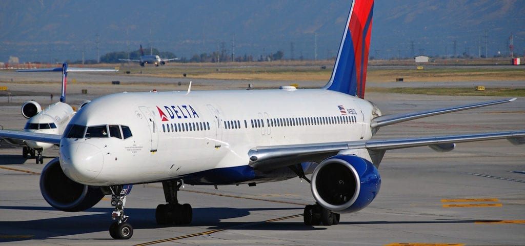 A Delta Airlines aircraft sits on the tarmac, waiting to be next in line for takeoff.
