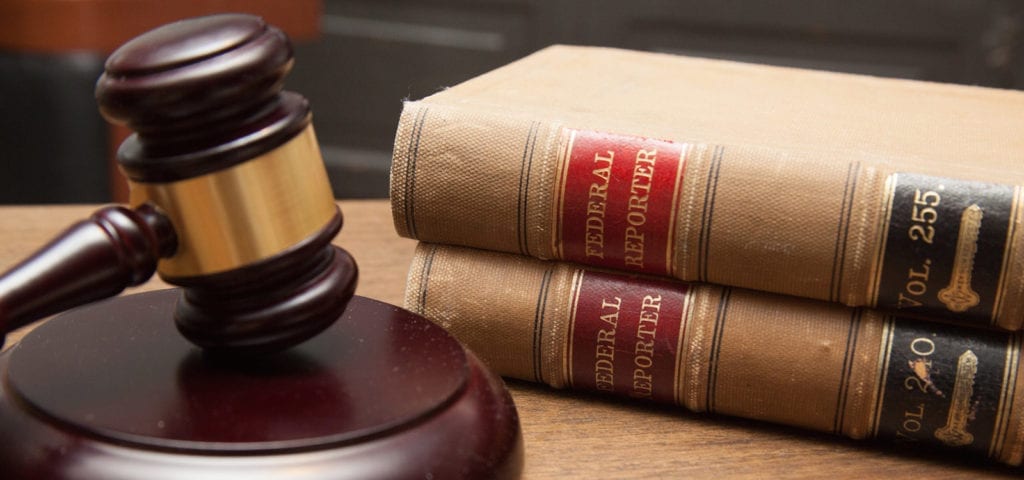 A judge's gavel rests on its pedestal next to a stack of legal books.