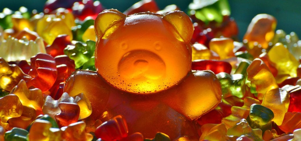 Candy gummy bears in a pile, surrounding the largest candy gummy bear of them all.