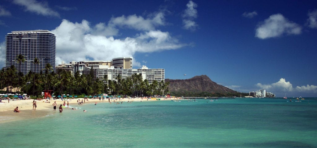 Hawaii vacationers on a beach on a sunny day.