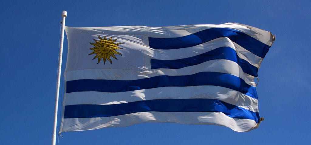 The national flag of Uruguay flying on a windy, cloudless day.