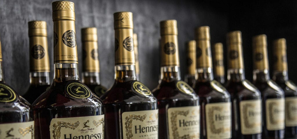 Bottles of Hennessy liquor lined up on the wall inside of a liquor store.